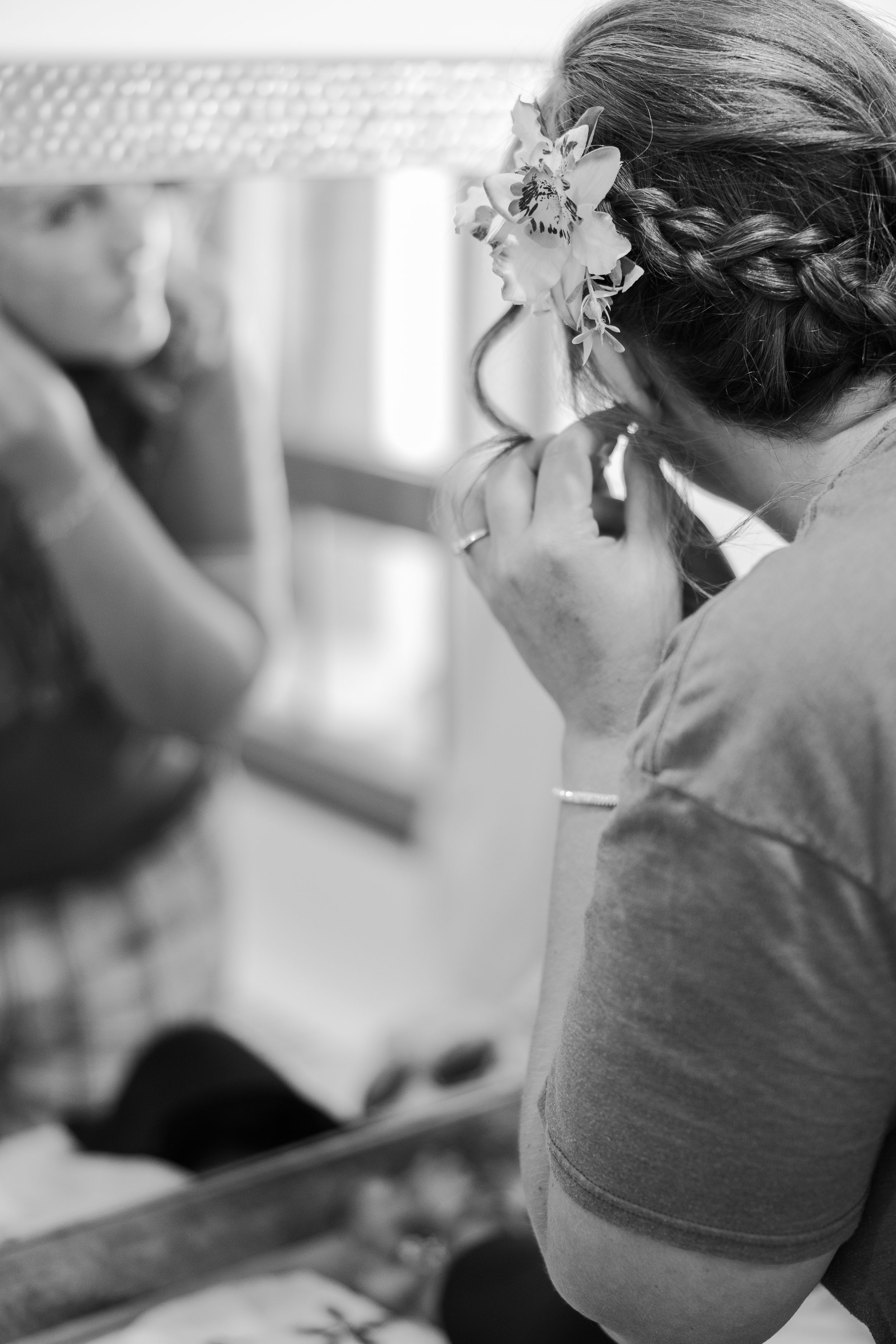 Bride getting ready for the ceremony preparing to put on her earrings in black and white.