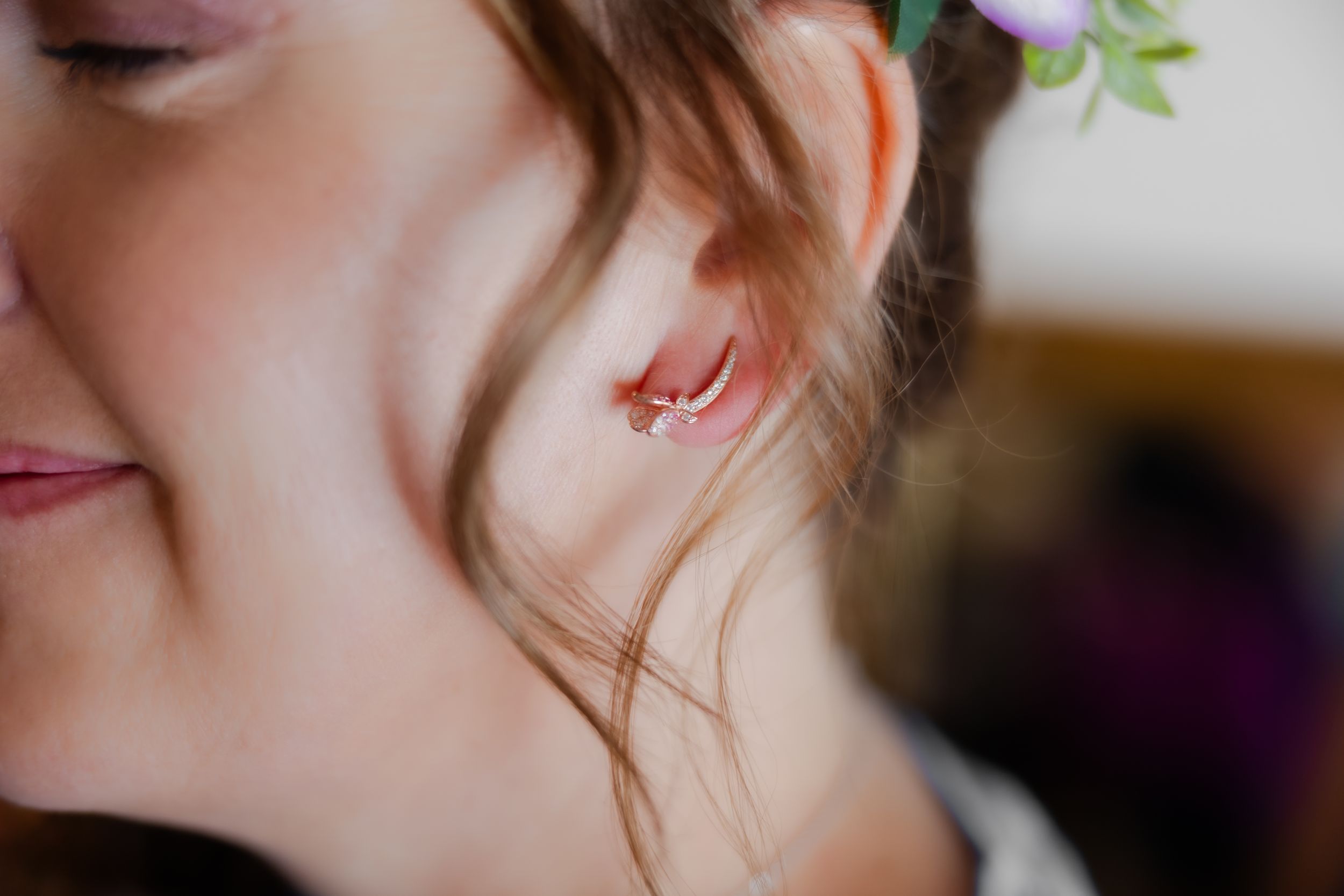 Close up of the side of a brides face and hair, emphasizing the rose gold earrings she just put on.
