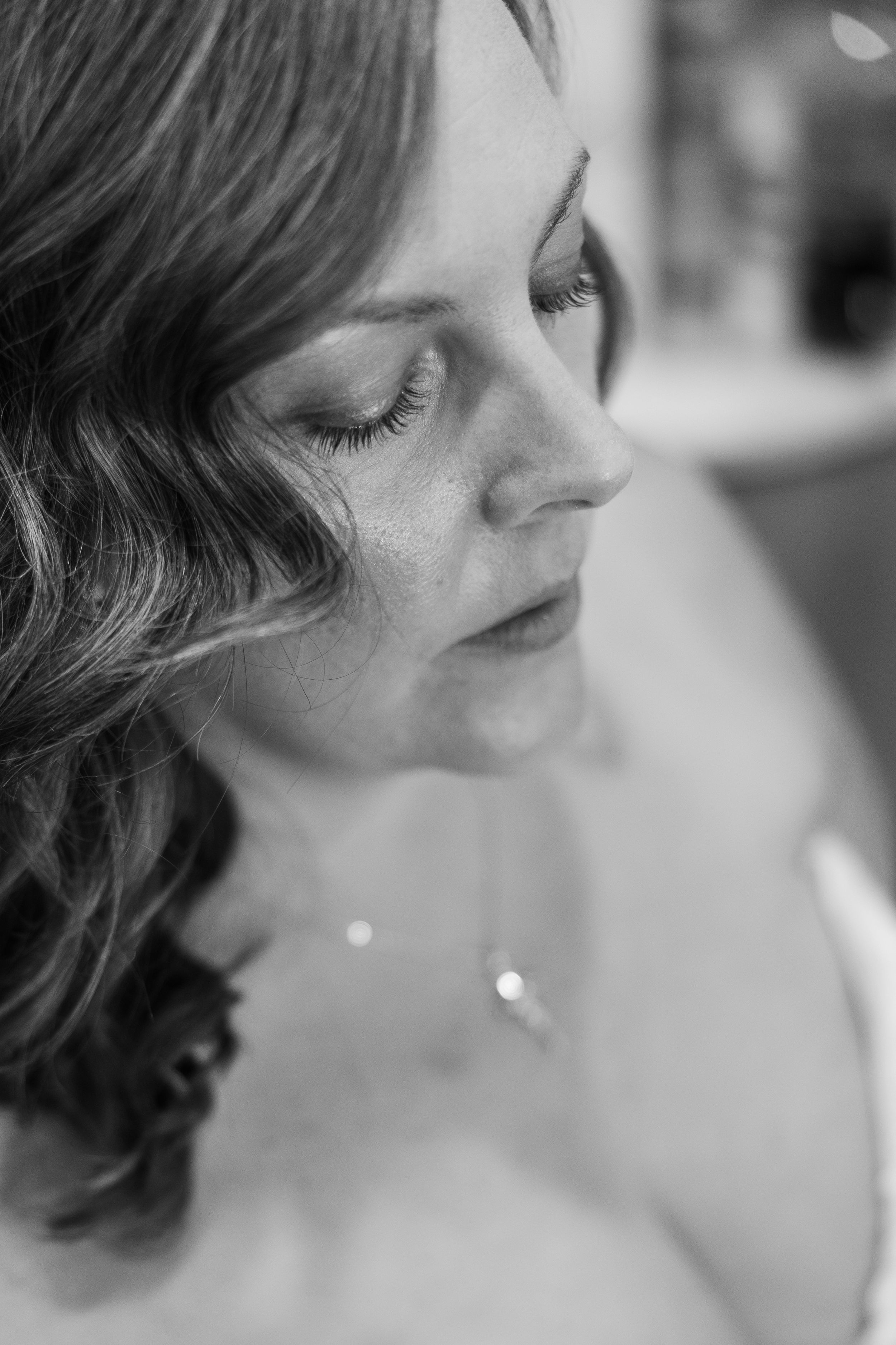 Close up looking down on a bride sitting in a chair getting ready for the ceremony. She is calm and serene.
