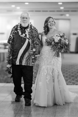 Bride and her father walking down the aisle towards her groom smiling out at her guests.