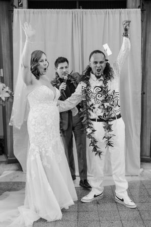Bride and groom standing at the alter after they have been announce husband and wife cheering with their hands up.