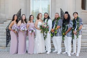 Bride and groom with bridal party standing in front of a set of stairs in an urban city setting.