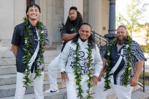 Groom and his groomsmen smiling proudly standing on stairs outside an urban city building.