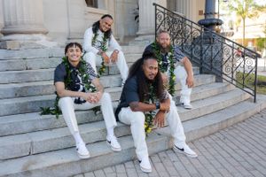 Groom and his groomsmen sitting on stairs outside an urban city building smiling proudly.