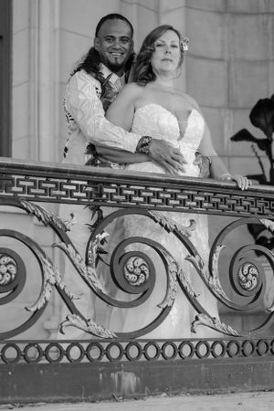 Groom embracing bride outside in the balcony of an urban city building in black and white.