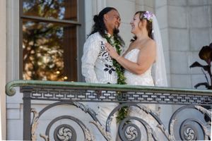 Bride an groom embracing and sharing a loving gaze outside in the balcony of an urban city building.