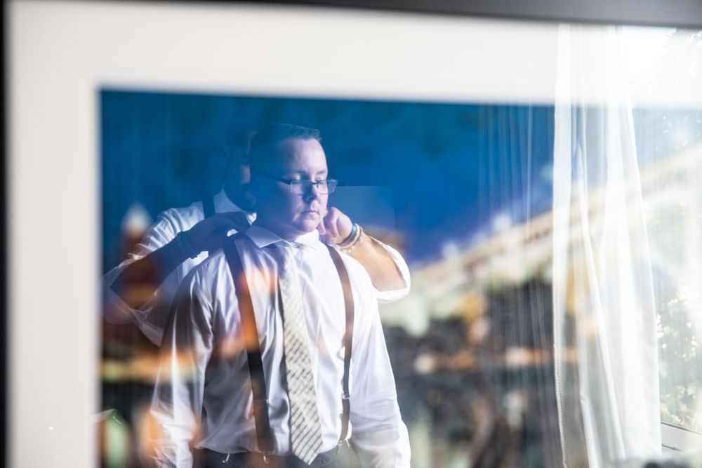Music performer in white shirt and suspenders against blue-tinted background.
