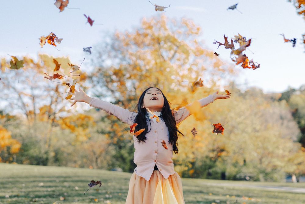 A girl threw leaves to the sky at the Larz Anderson Park, Brookline, MA.