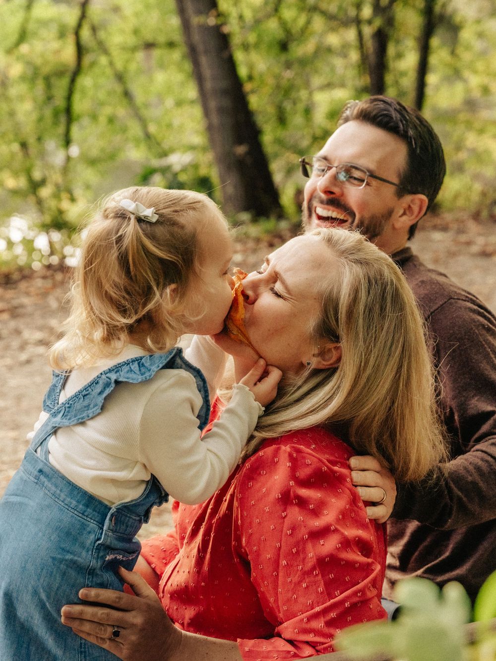 Candid family moments captured during a fall photoshoot in a park with natural lighting and laughter at Menotomy Rocks Park in Arlington.