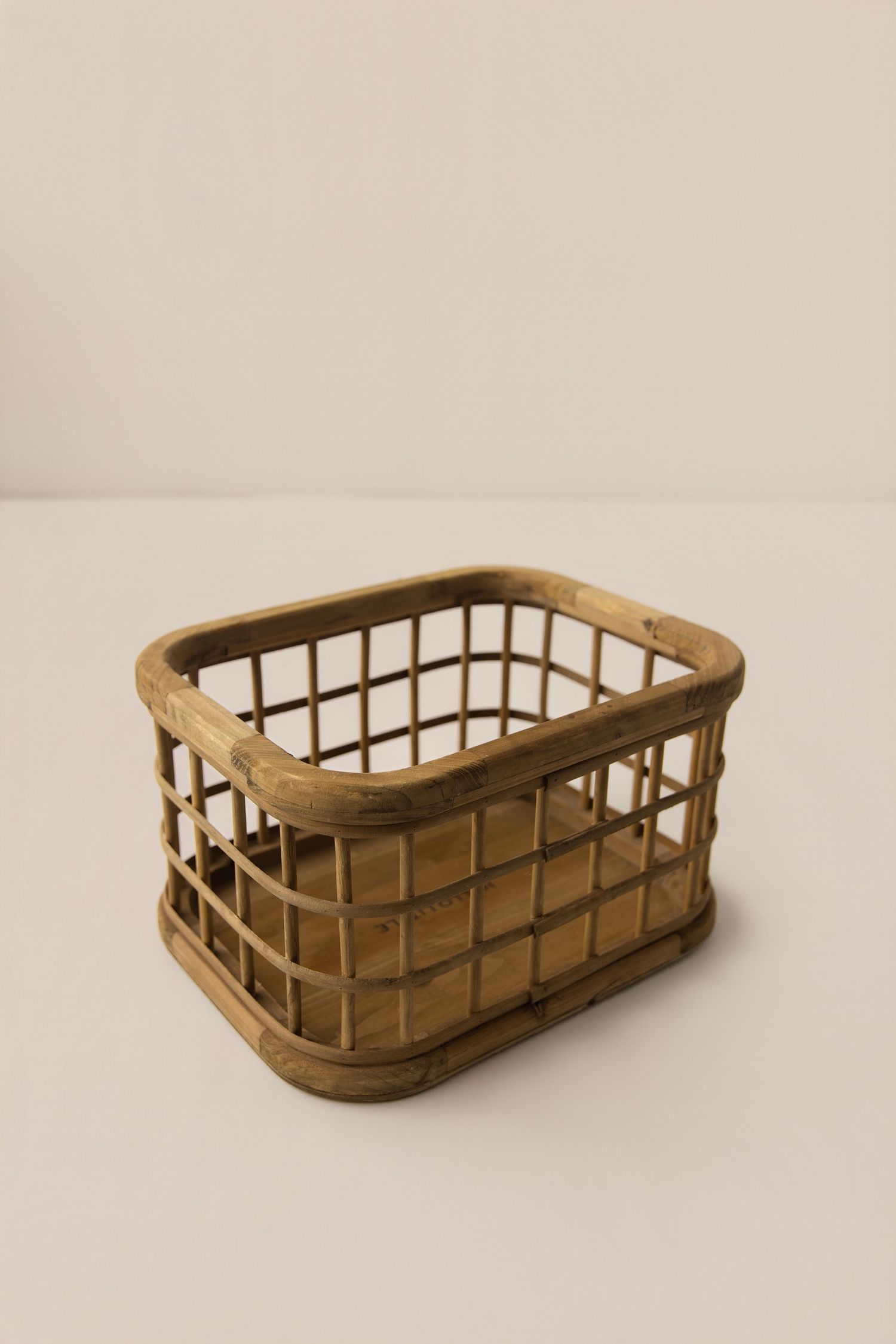 Small rectangular woven rattan storage basket with grid pattern sides and wooden frame on white background.