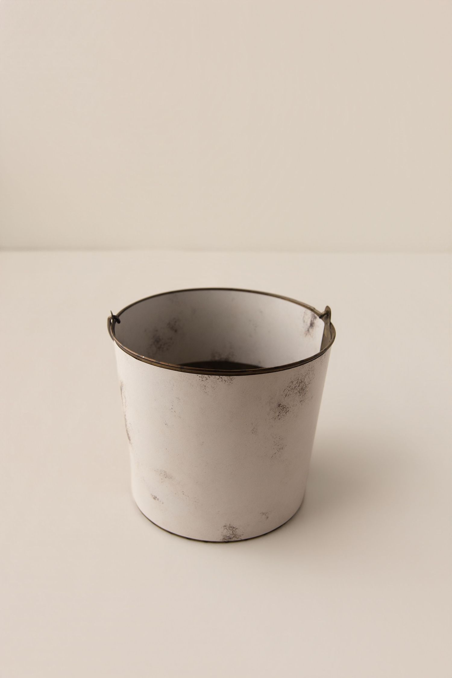 Vintage white distressed metal bucket with rustic brown edges, perfect for rustic home decor or plant pot use.