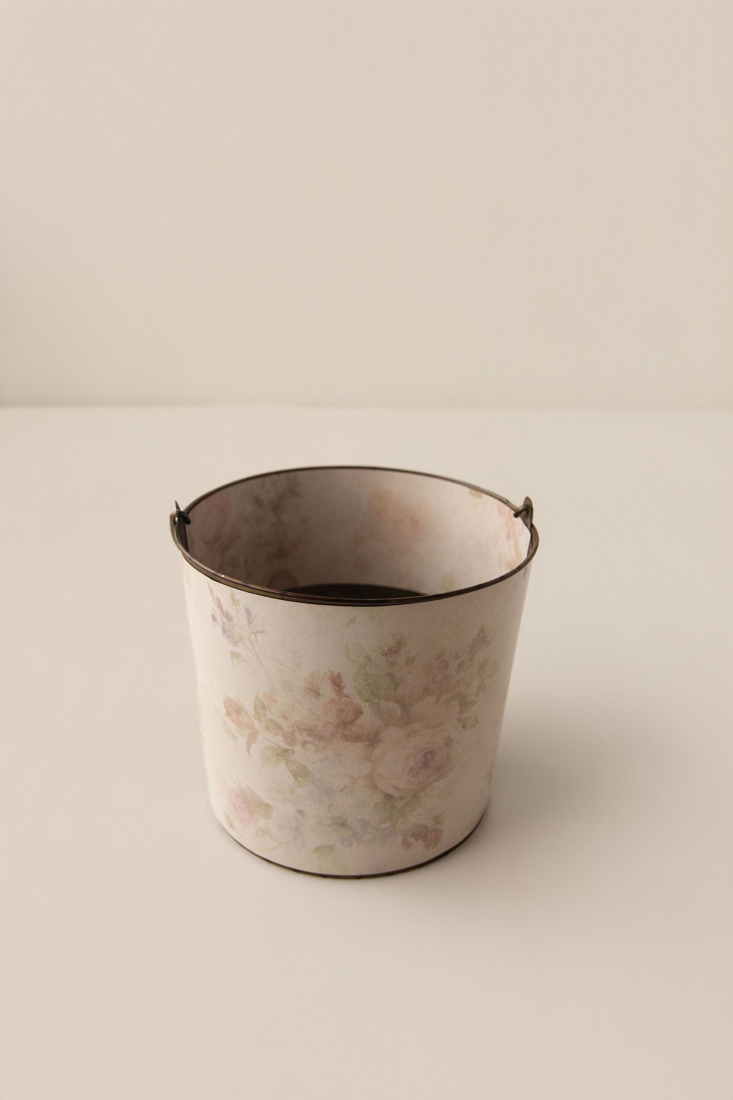 Vintage floral metal bucket with distressed finish, featuring soft pink roses on cream background with aged patina rim.