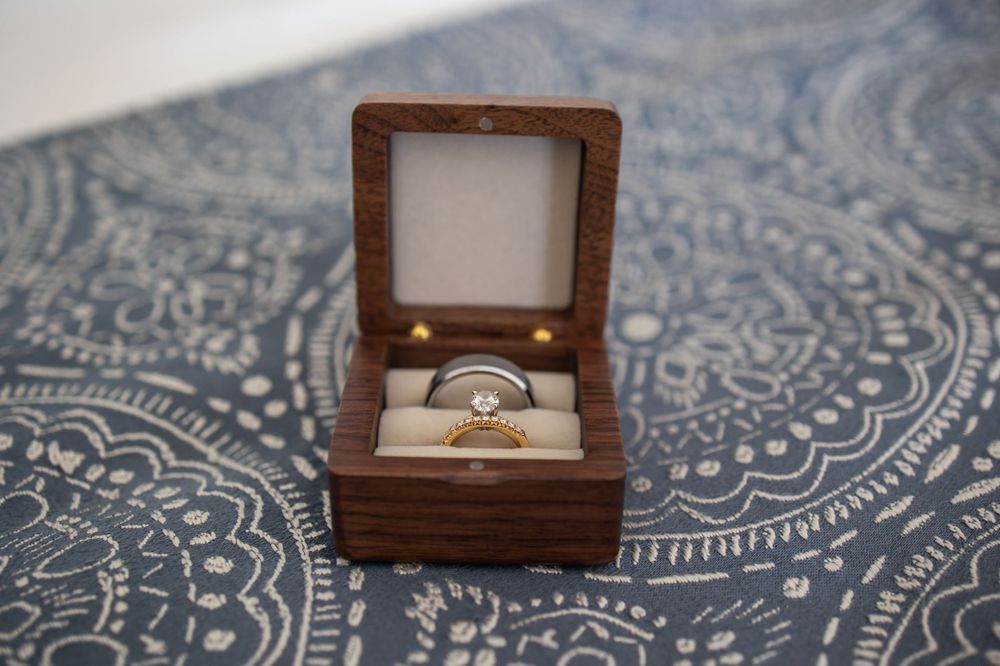 Wedding ring displayed in a small wooden box on a patterned blue textile.
