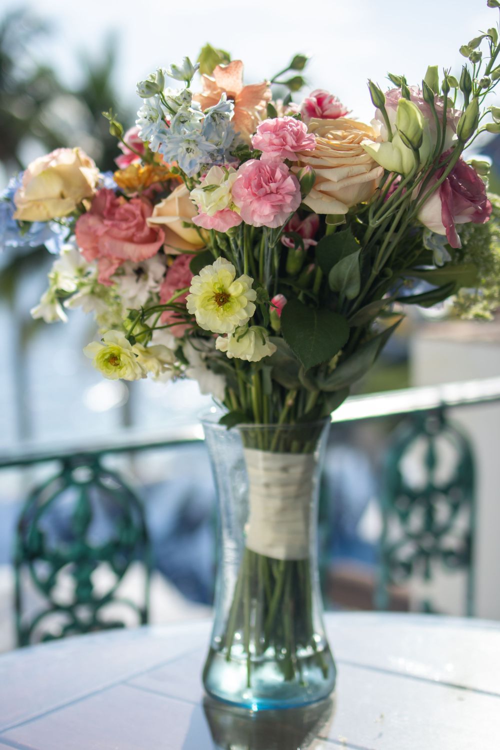 Colorful bouquet of mixed flowers in a clear glass vase on a white table.
