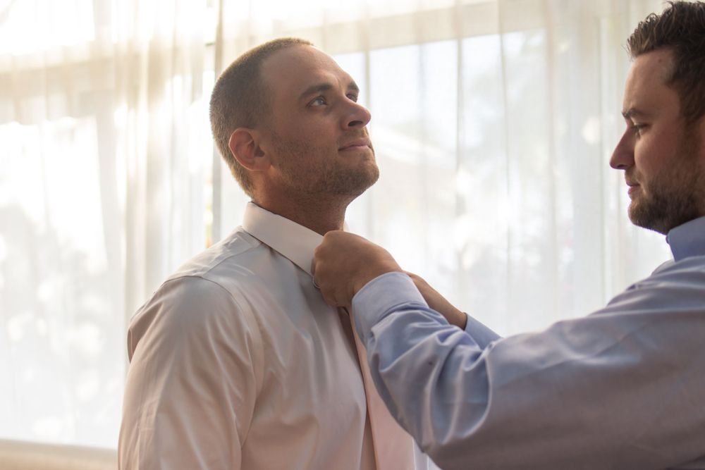 Two people adjusting formal attire in preparation for an event.