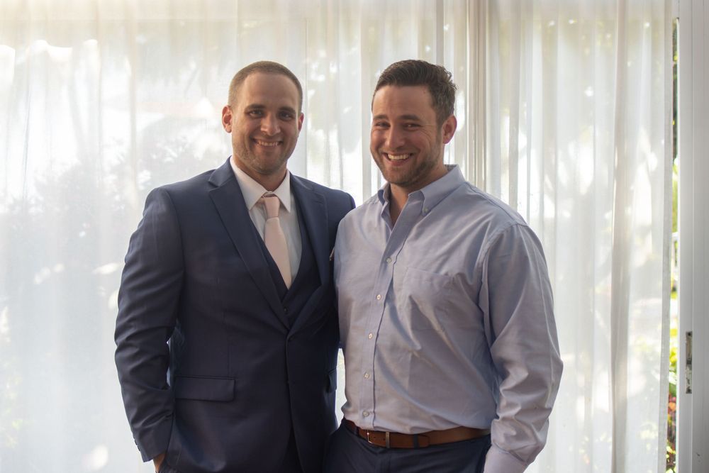 Two people in formal attire posing together against a white backdrop.