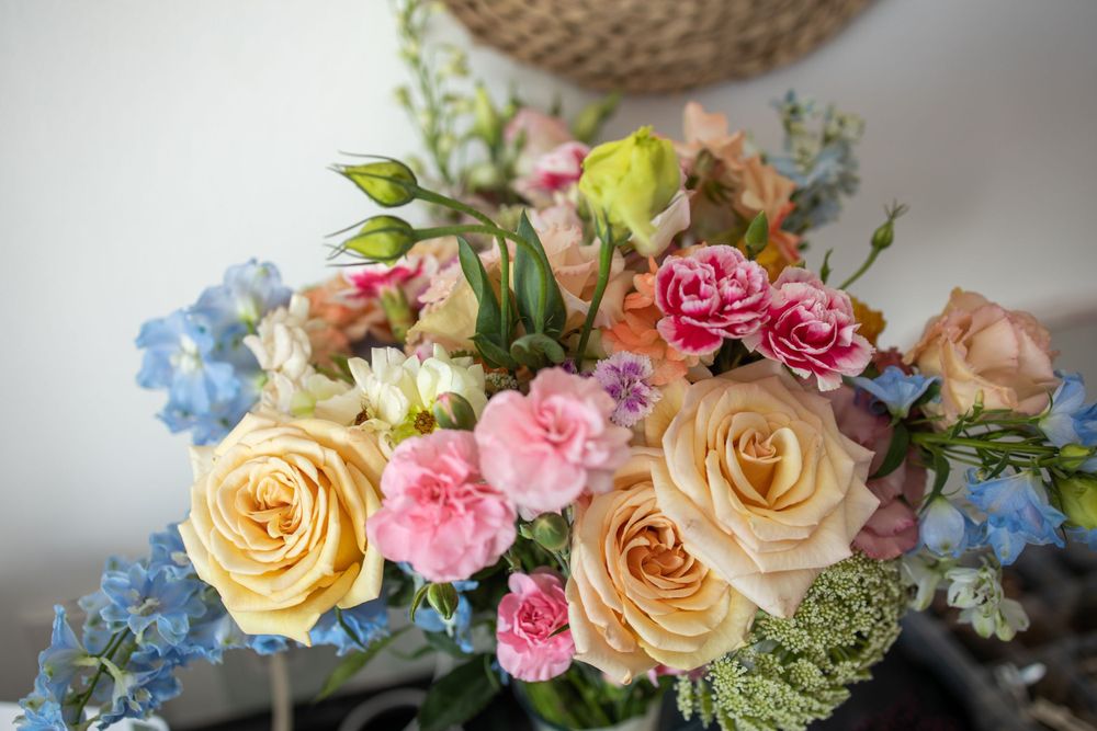 Elegant wedding bouquet with peach roses, pink carnations, and blue hydrangeas.