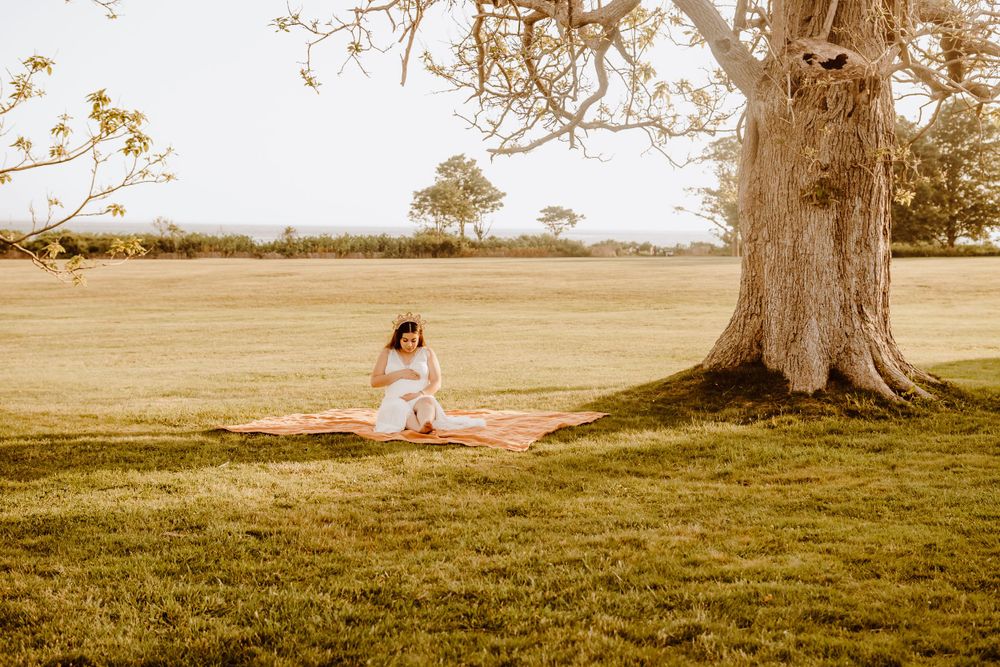 A white dress sits beneath a large oak tree in a sunny meadow.