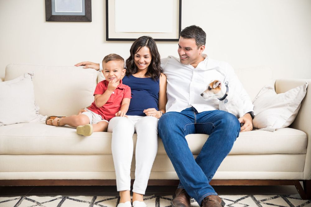 happy family sits together with their dog, content & laughing. they are covered with the best health & life insurance