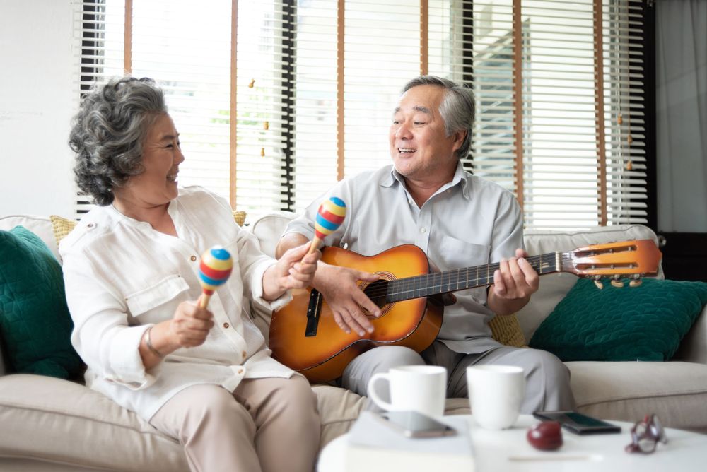 older couple sings together on their couch while he plays the guitar. They are joyful to not worry about their insurance