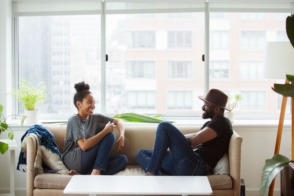 Young couple sits together on the couch chatting about how wonderful their experience with Smithree Insurance policy