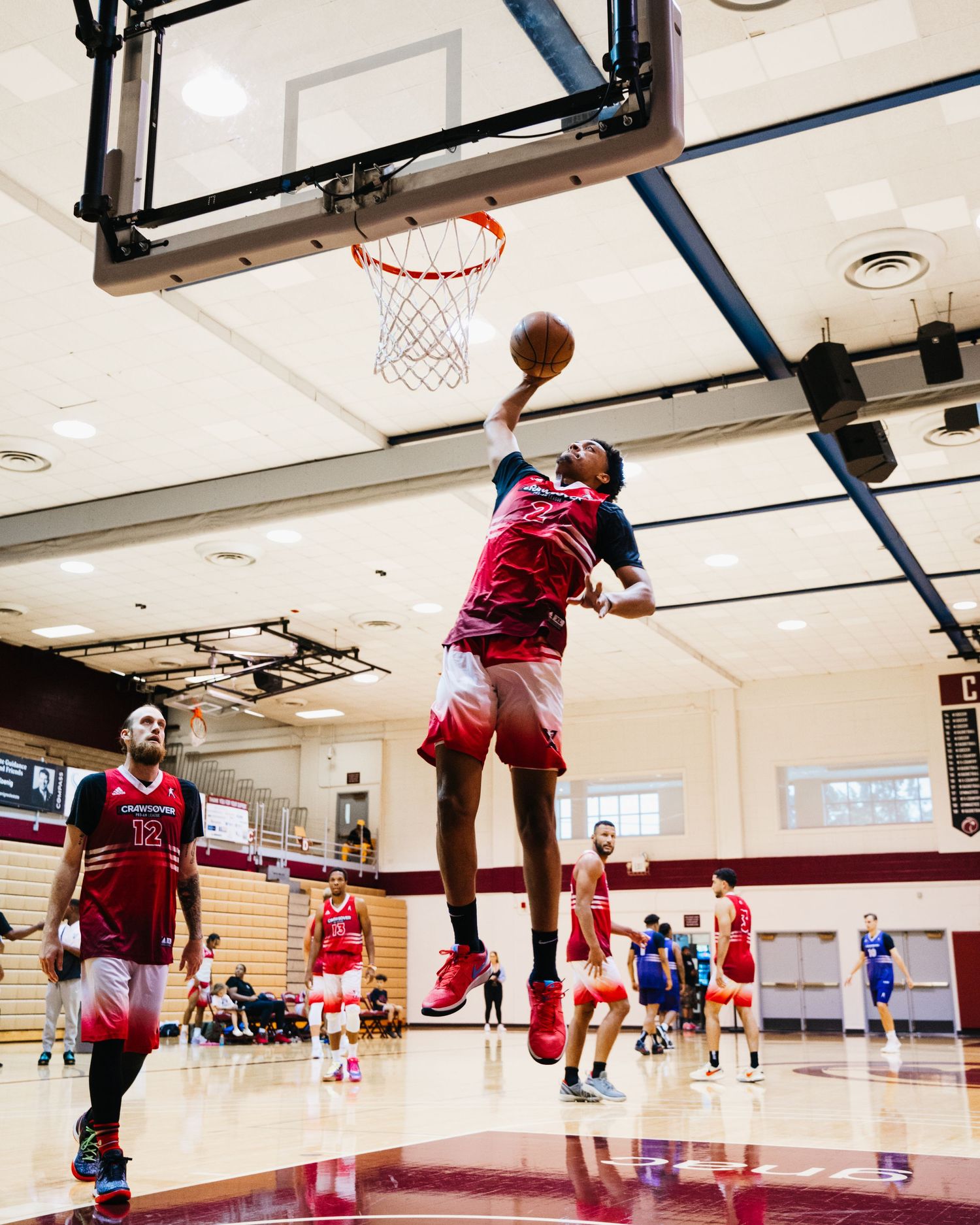 Basketball player in red jersey soars high for a dunk during an indoor game.