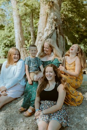 Candid family photography in the Texas Hill Country, featuring a mom and her kids sharing a joyful moment under cypress trees in Wimberley
