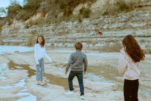 Colorful photo of kids playing by the river in an an outdoor family photo shoot in Central Texas.