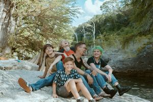 Lifestyle family photography in Wimberley, TX, featuring a dad and his kids laughing together by the water in the Texas Hill Country.