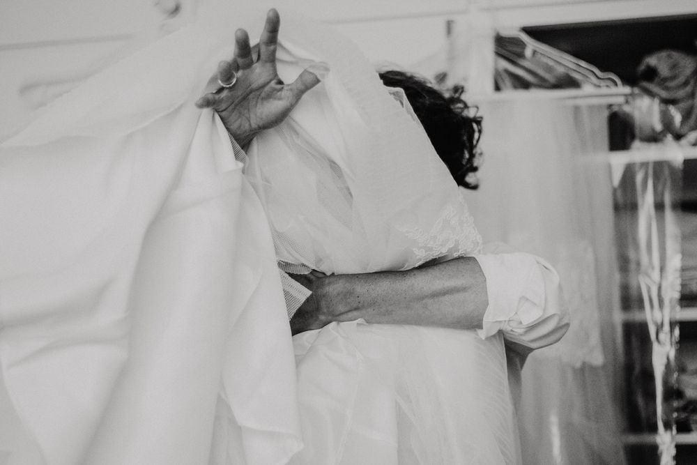 Black and white photo of a bride and groom sharing a tender embrace on their wedding day.