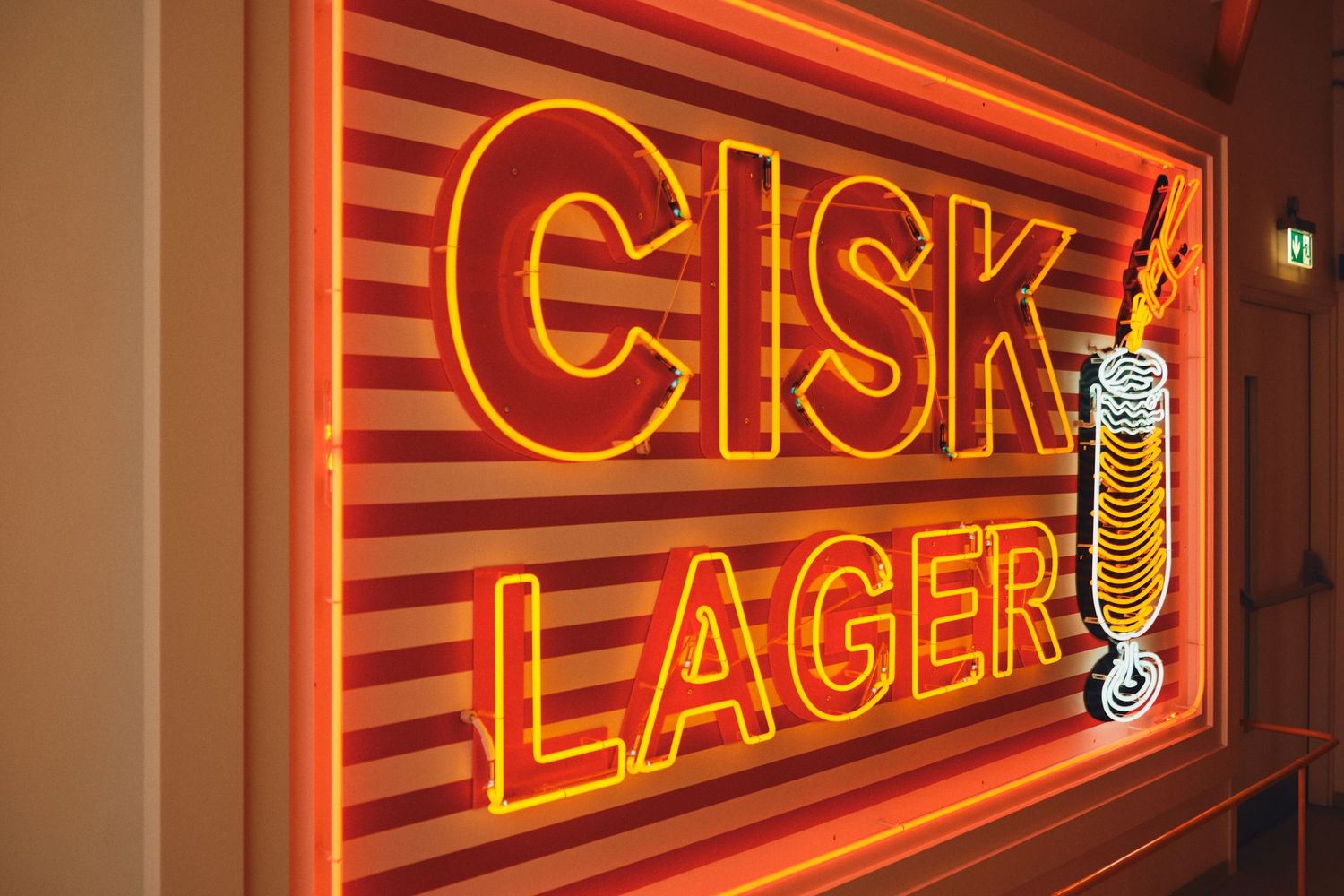Illuminated orange and red neon Cisk Lager sign with beer glass icon.