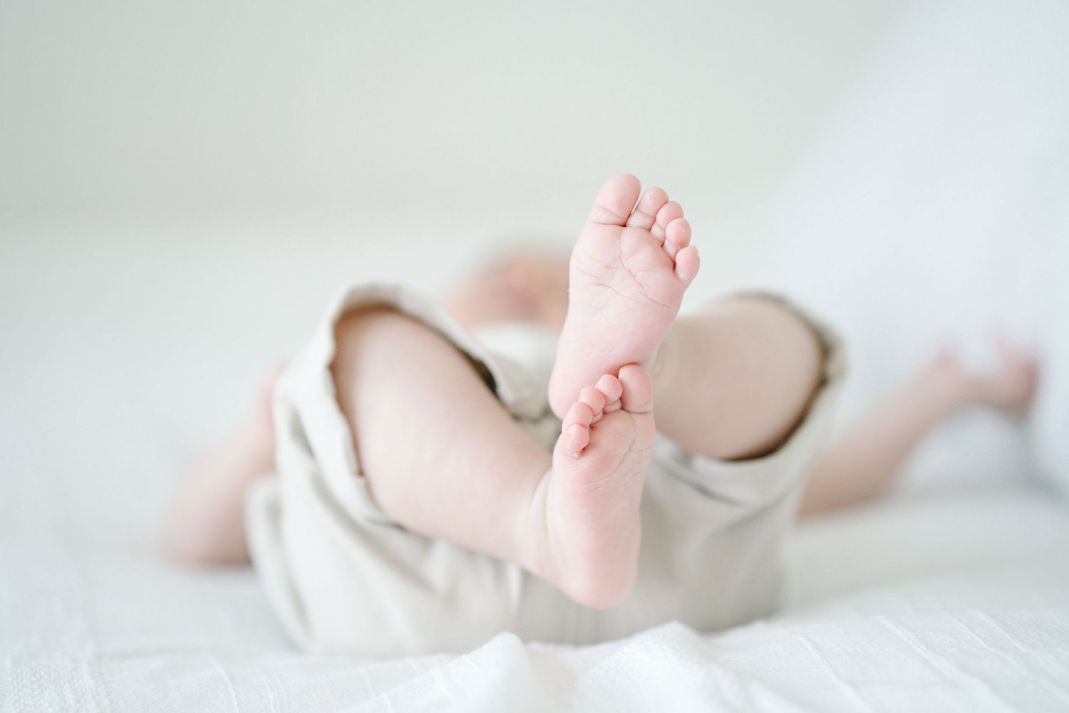 Close-up of tiny baby feet against white bedding.