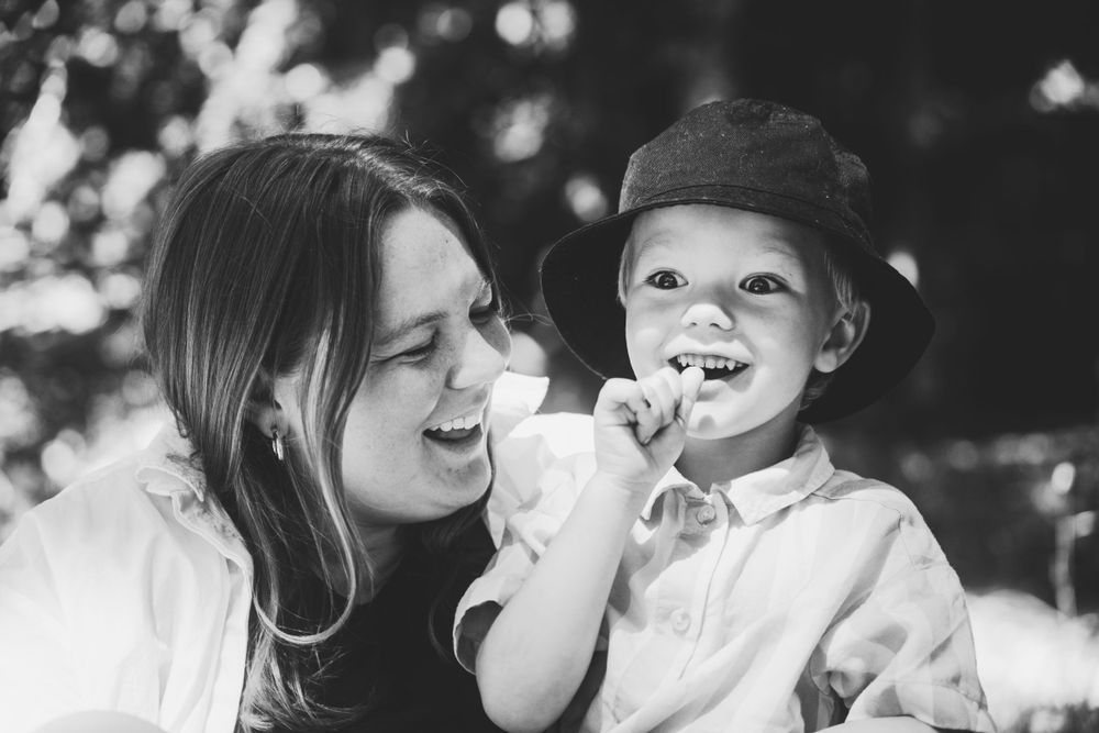 Black and white candid moment of shared joy between parent and child outdoors.
