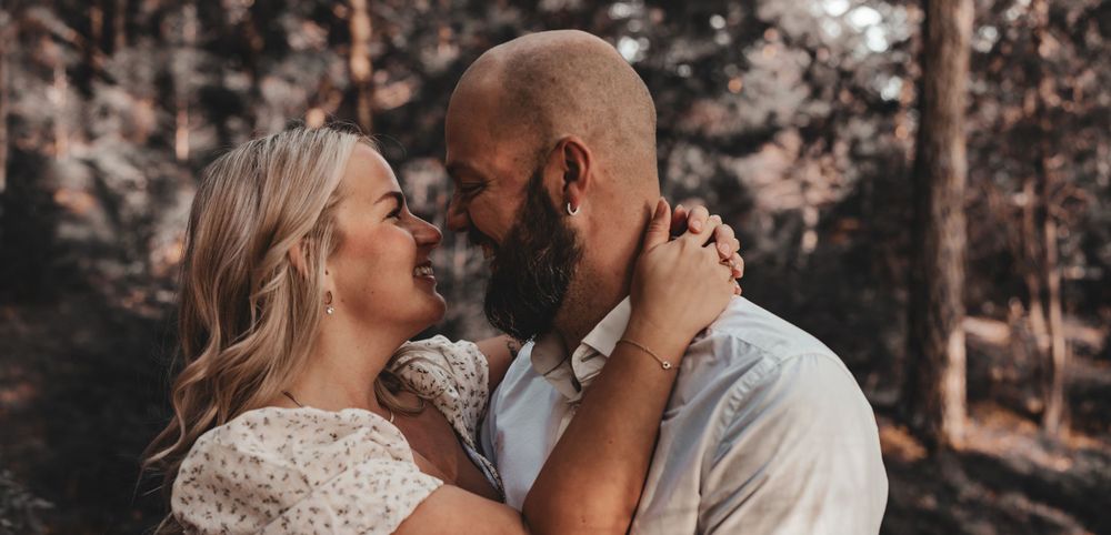 Romantic forest engagement photo of couple in warm evening light.