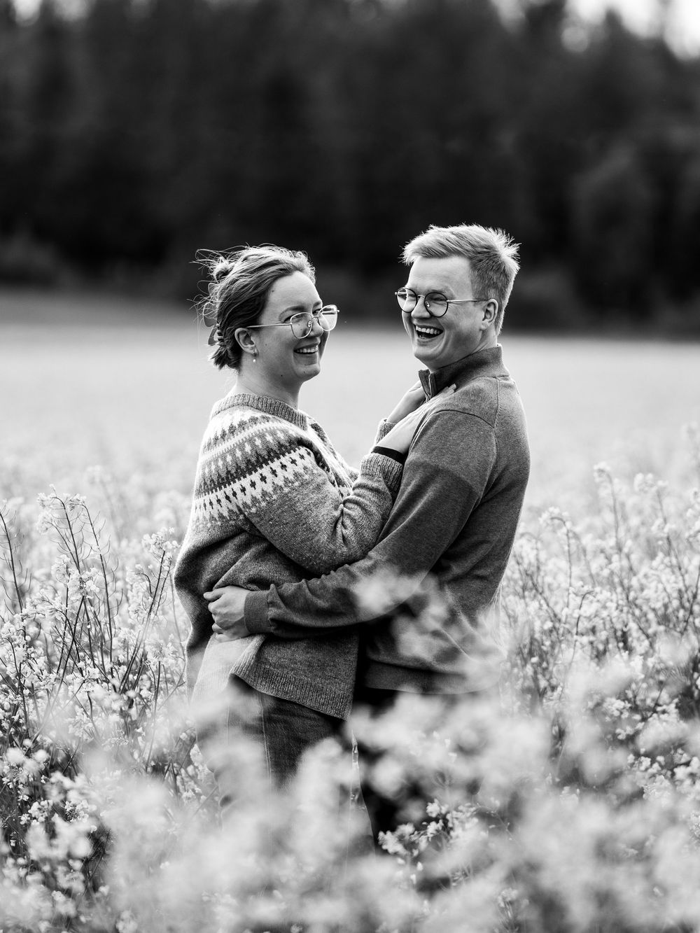 A couple laughing together in a blooming flower field shown in black and white sequence of candid moments.