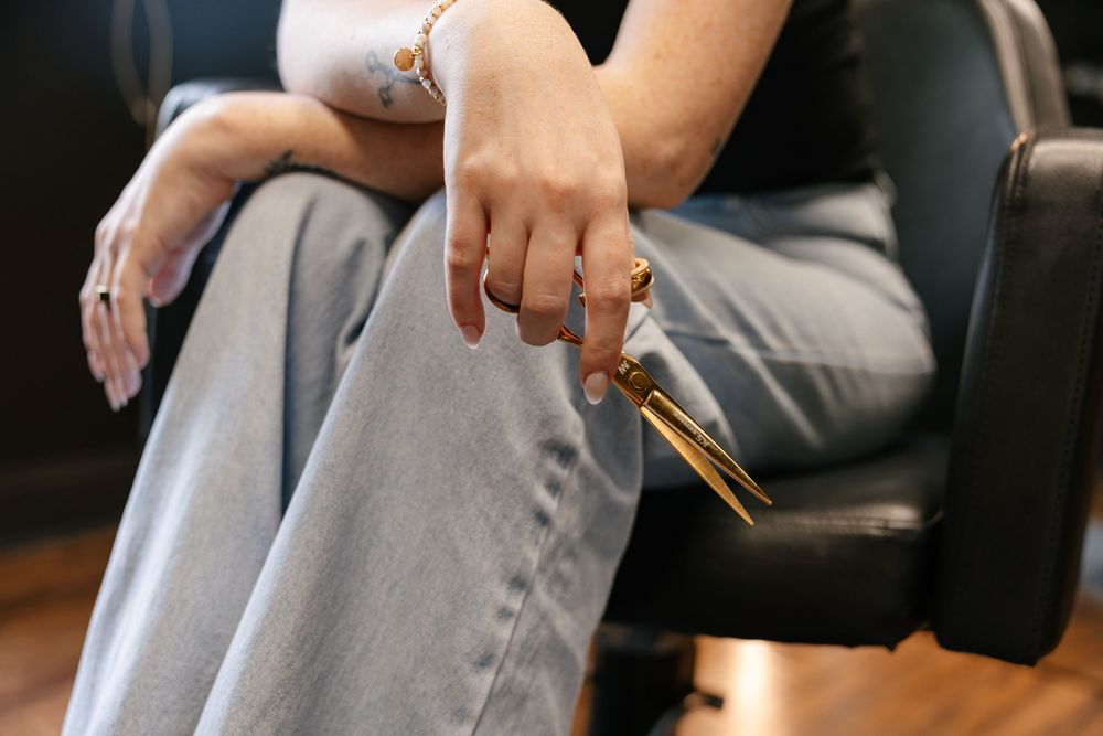 Close-up of hands resting on grey pants while sitting in black chair.