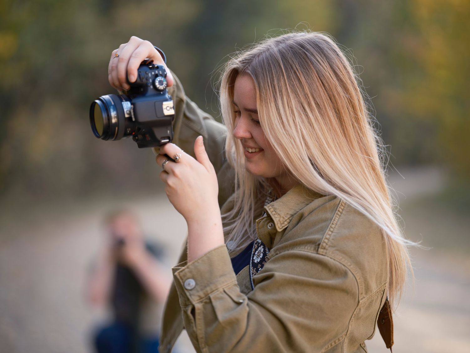 Jessica Easton holding a camera doing outdoor photography and smiling