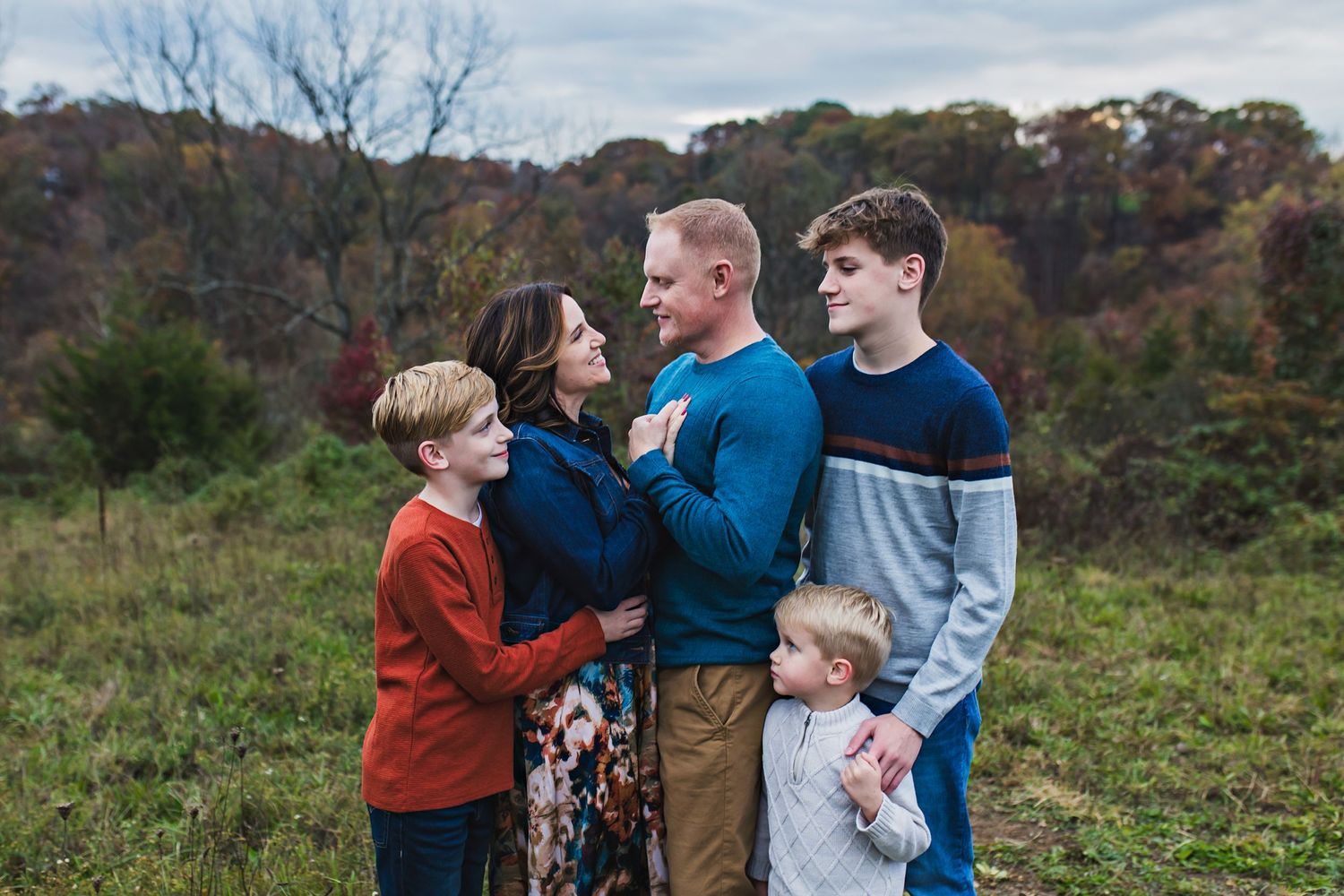Family standing outdoors wearing blue, orange, and cream color palette for their family photos