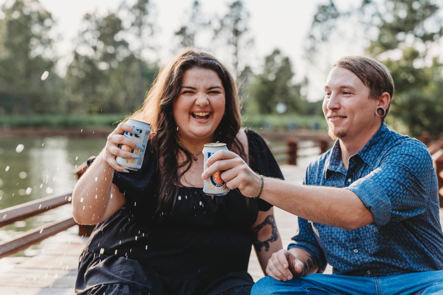 Couple sharing laughs during outdoor photo session in natural setting.