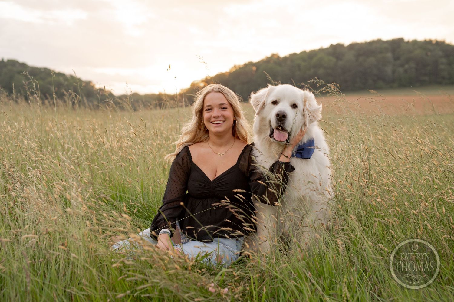 Joyful outdoor portrait with a friendly white dog in a summer meadow at sunset.