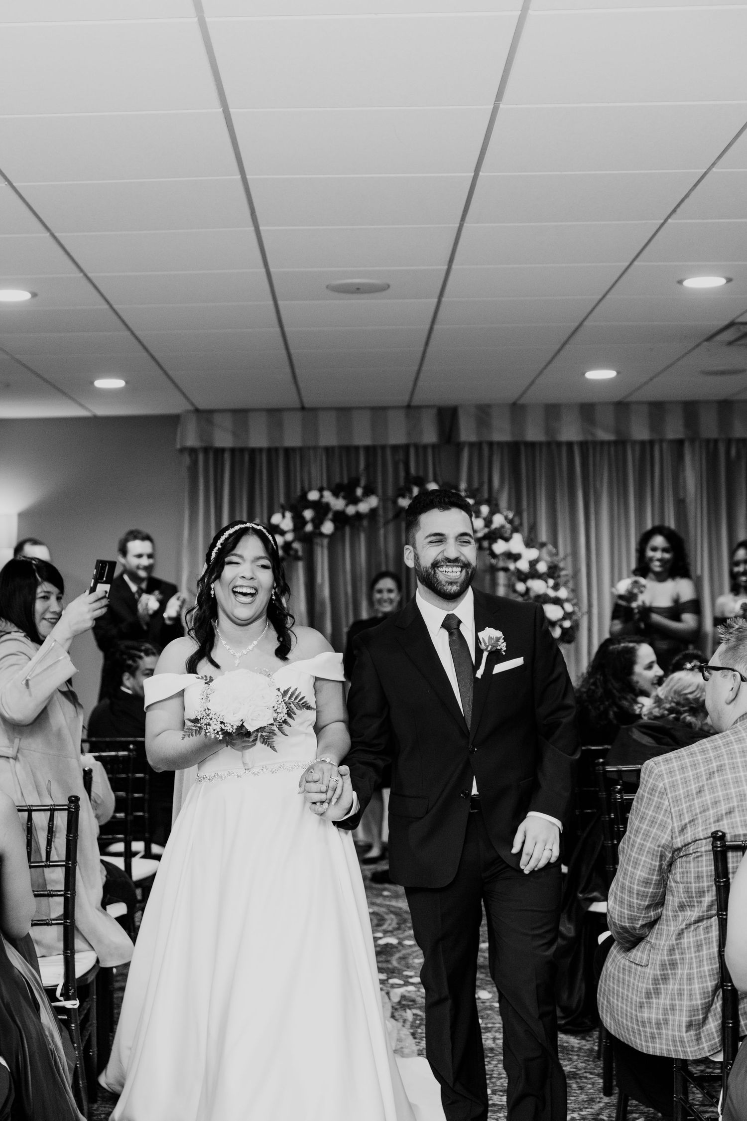 A newly married couple walking down the aisle at their indoor wedding ceremony.