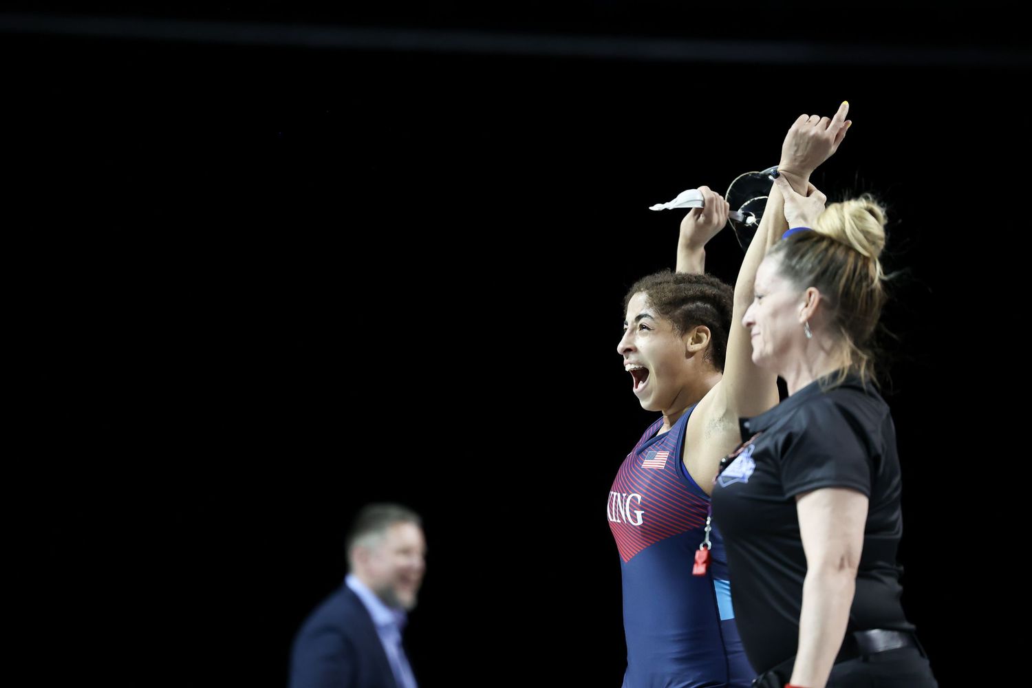 Two athletes celebrate on the winners podium at a wrestling championship event.