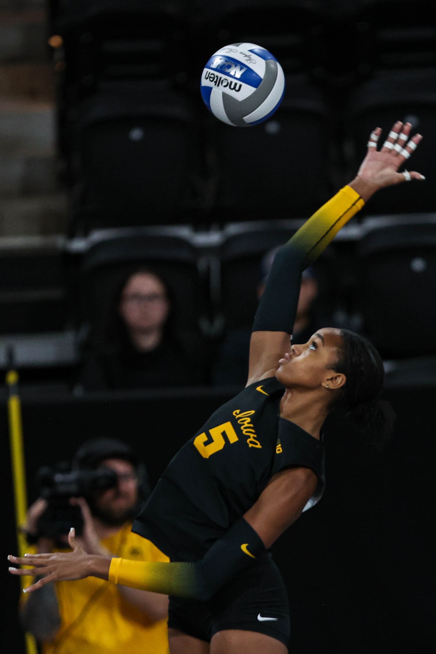 Volleyball player in black jersey leaps to hit ball during intense match.