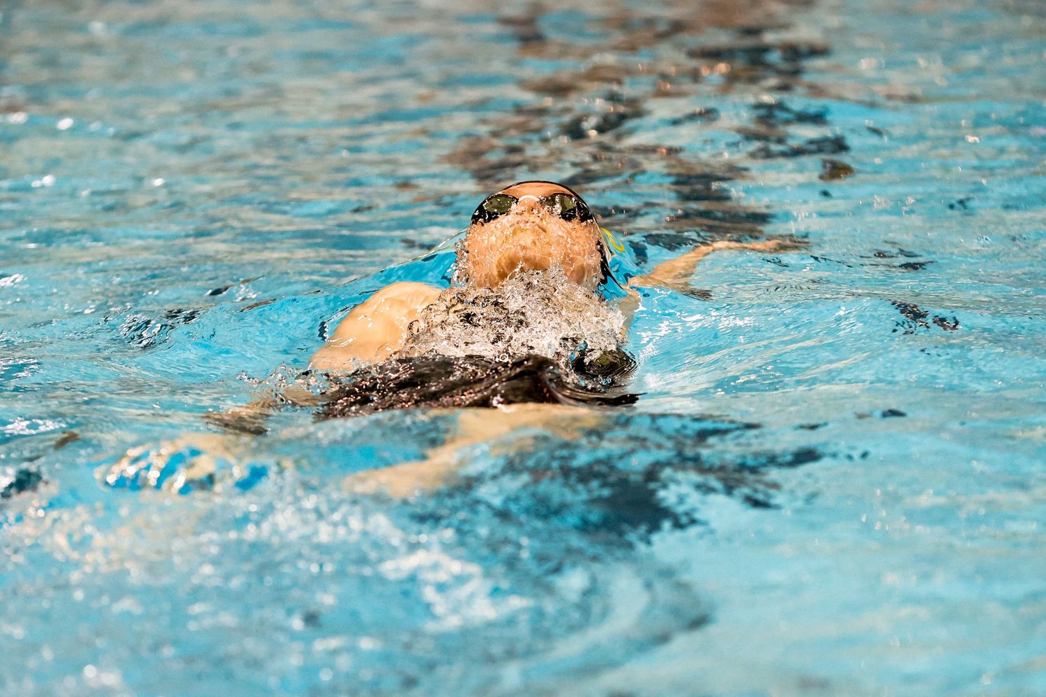 Swimmer performs breaststroke in competitive pool race.
