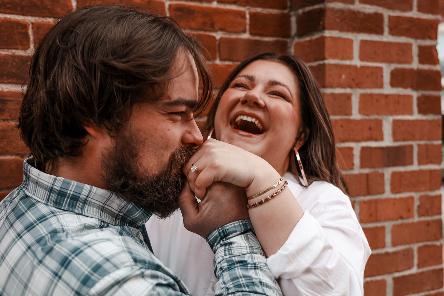 A candid moment of laughter against a brick wall background.