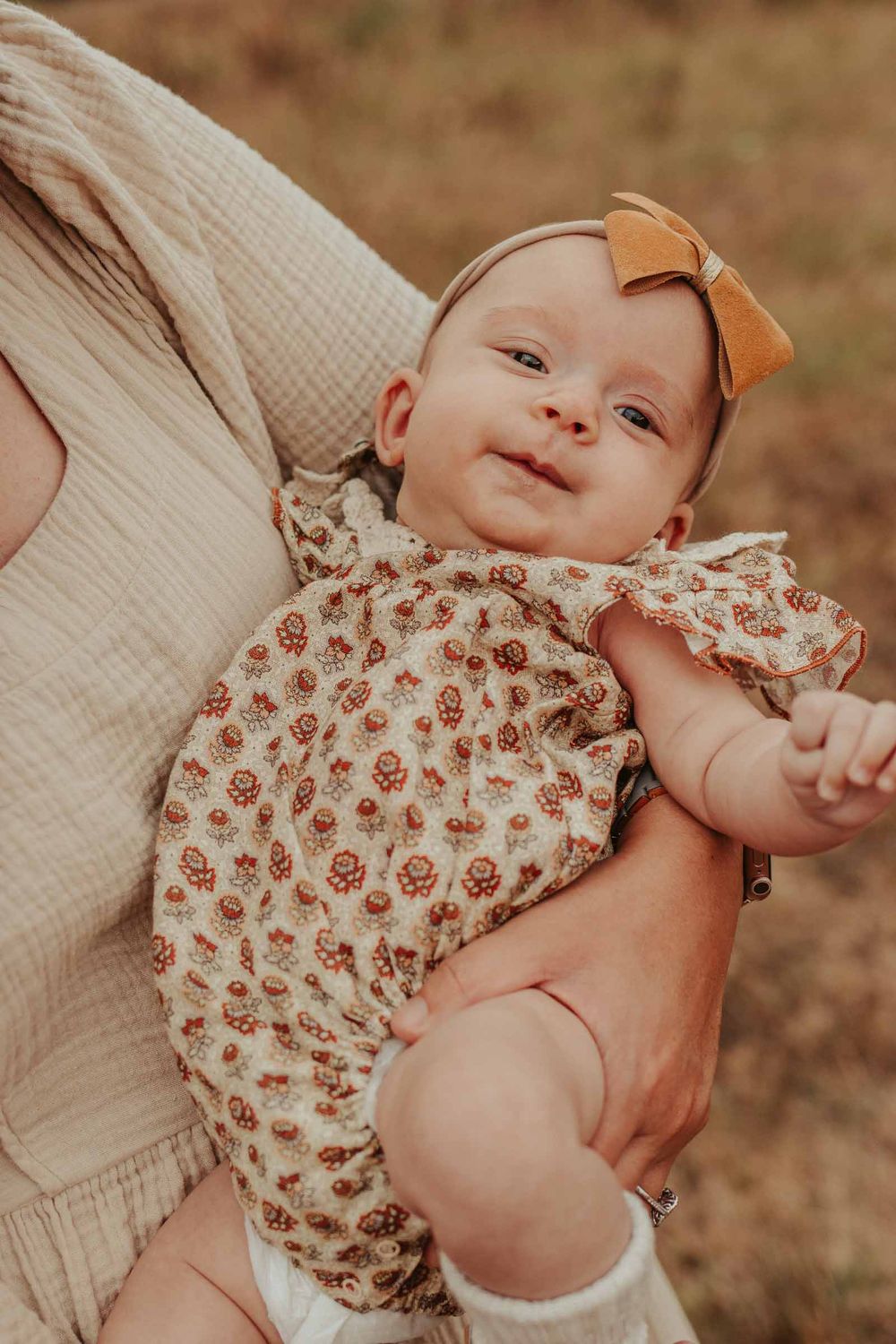 baby girl with a bow headband being held by mom and dad
