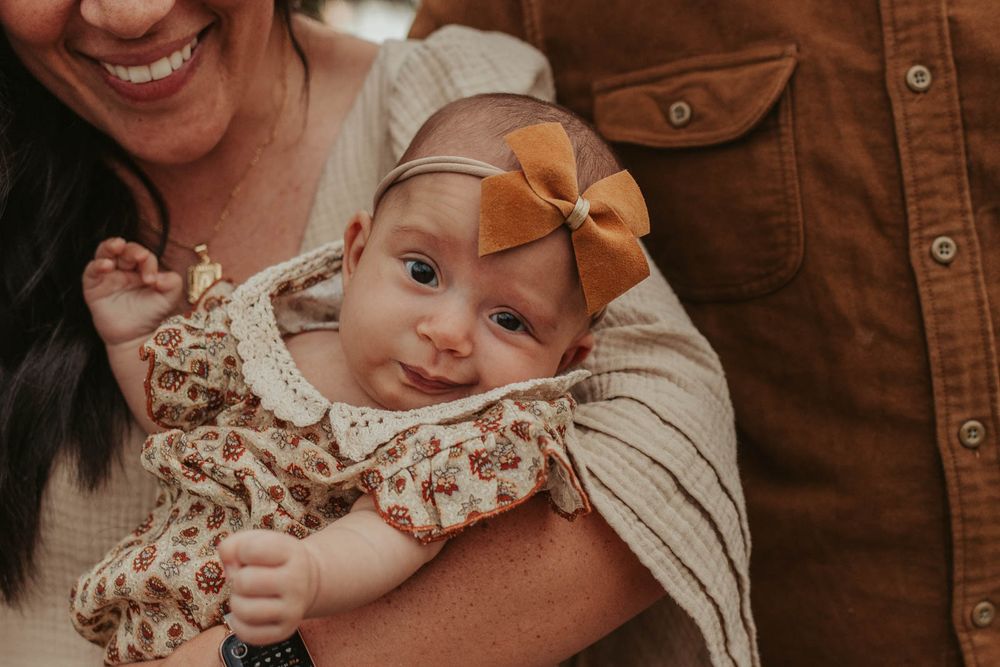 baby girl with a bow headband being held by mom and dad
