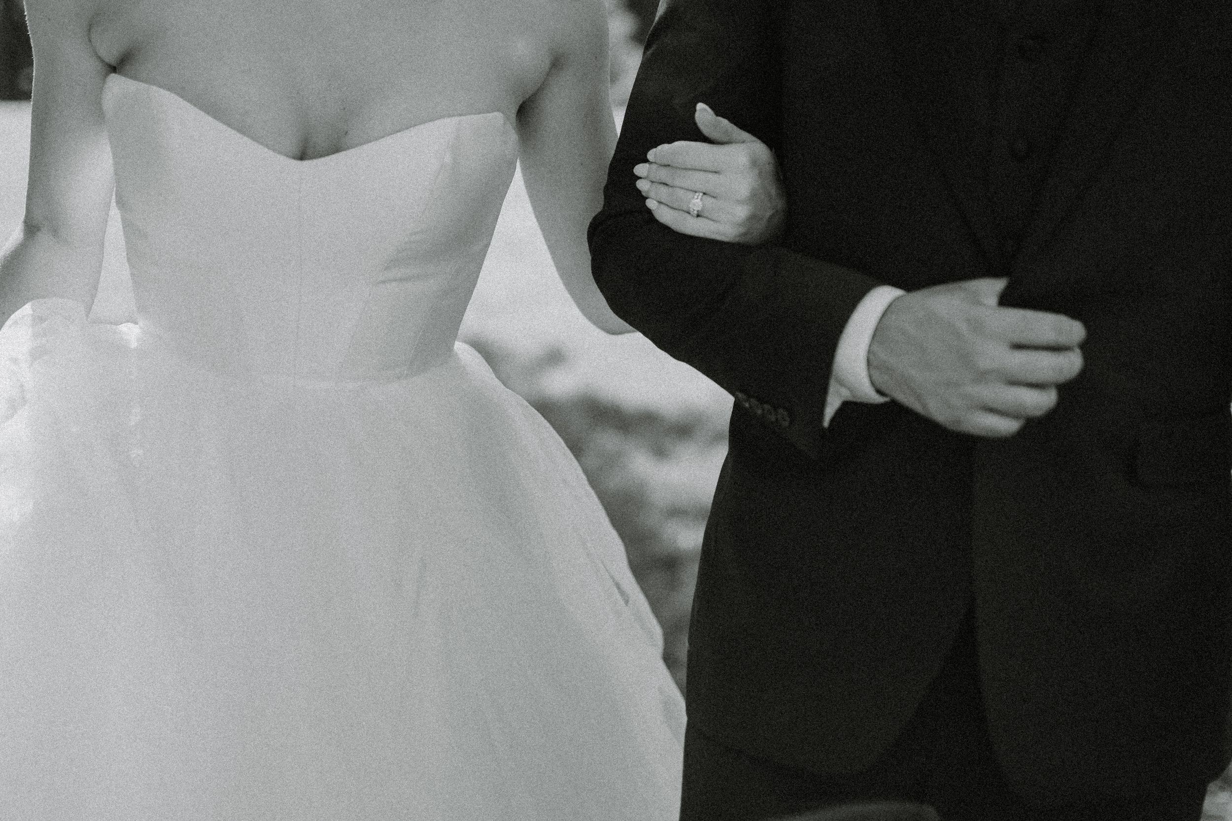 Black and white detail shot of bride's strapless dress and groom's suit.