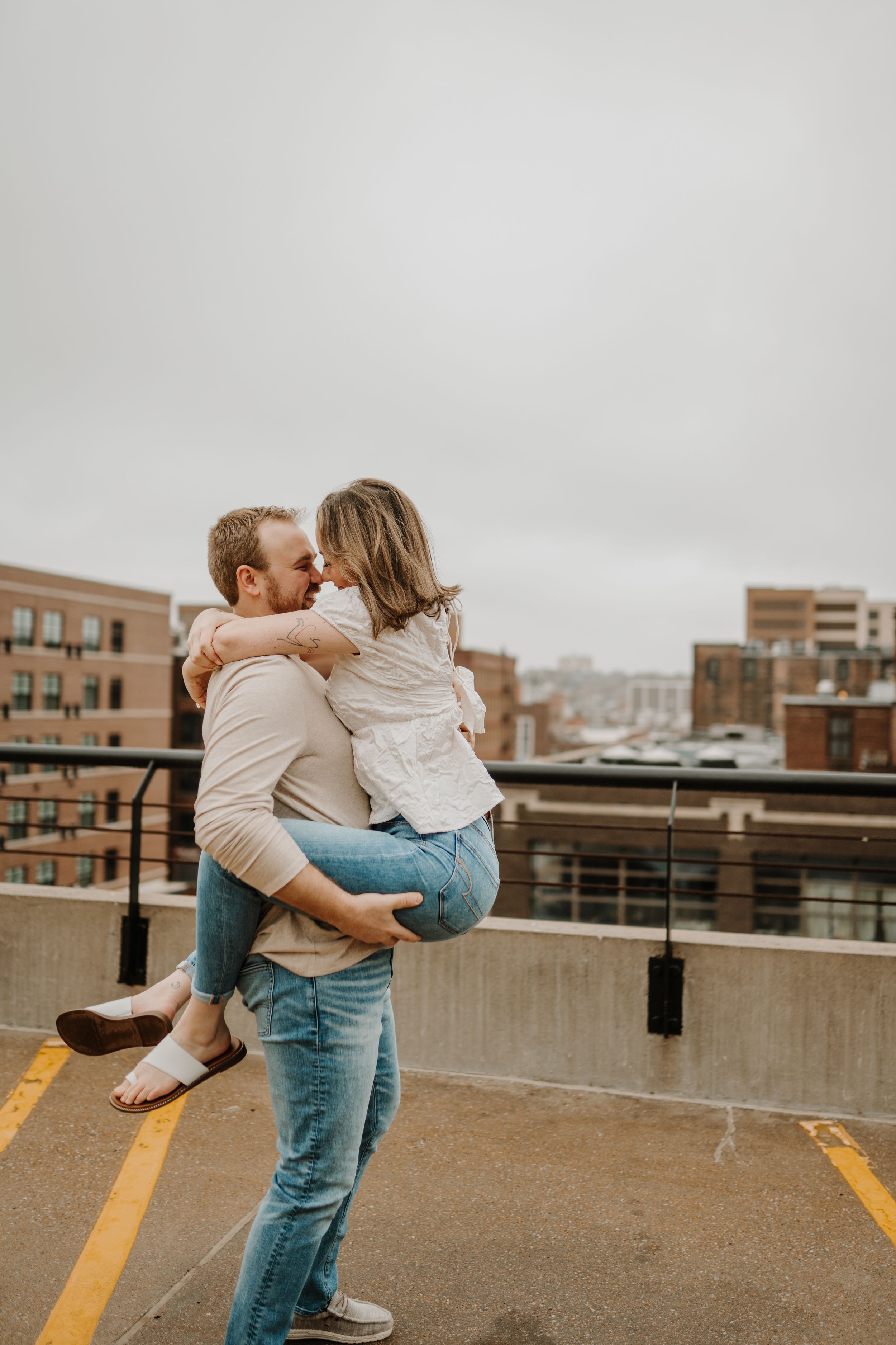 Playful couple in casual attire sharing affectionate moments on an urban rooftop.