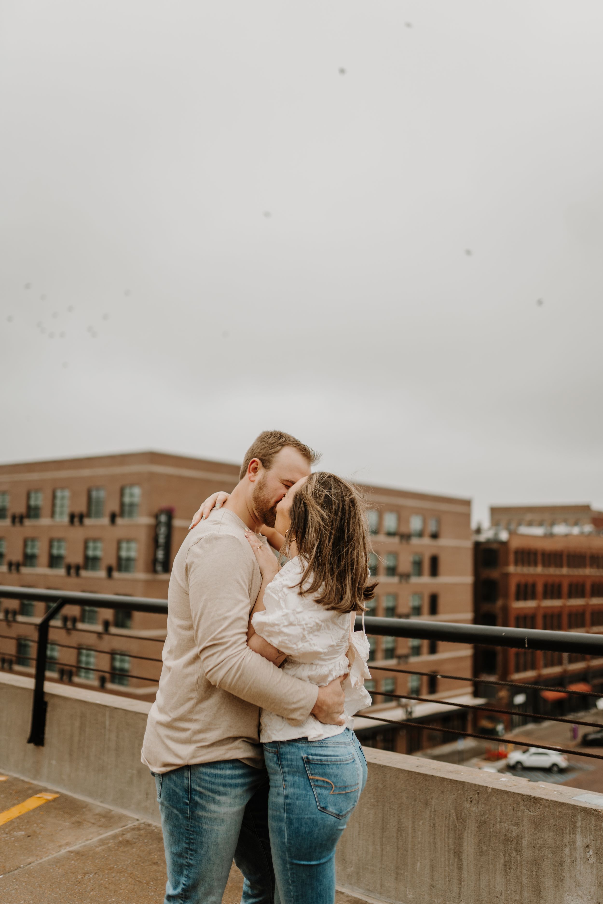 Romantic couple shoot on urban rooftop parking structure showing candid moments.